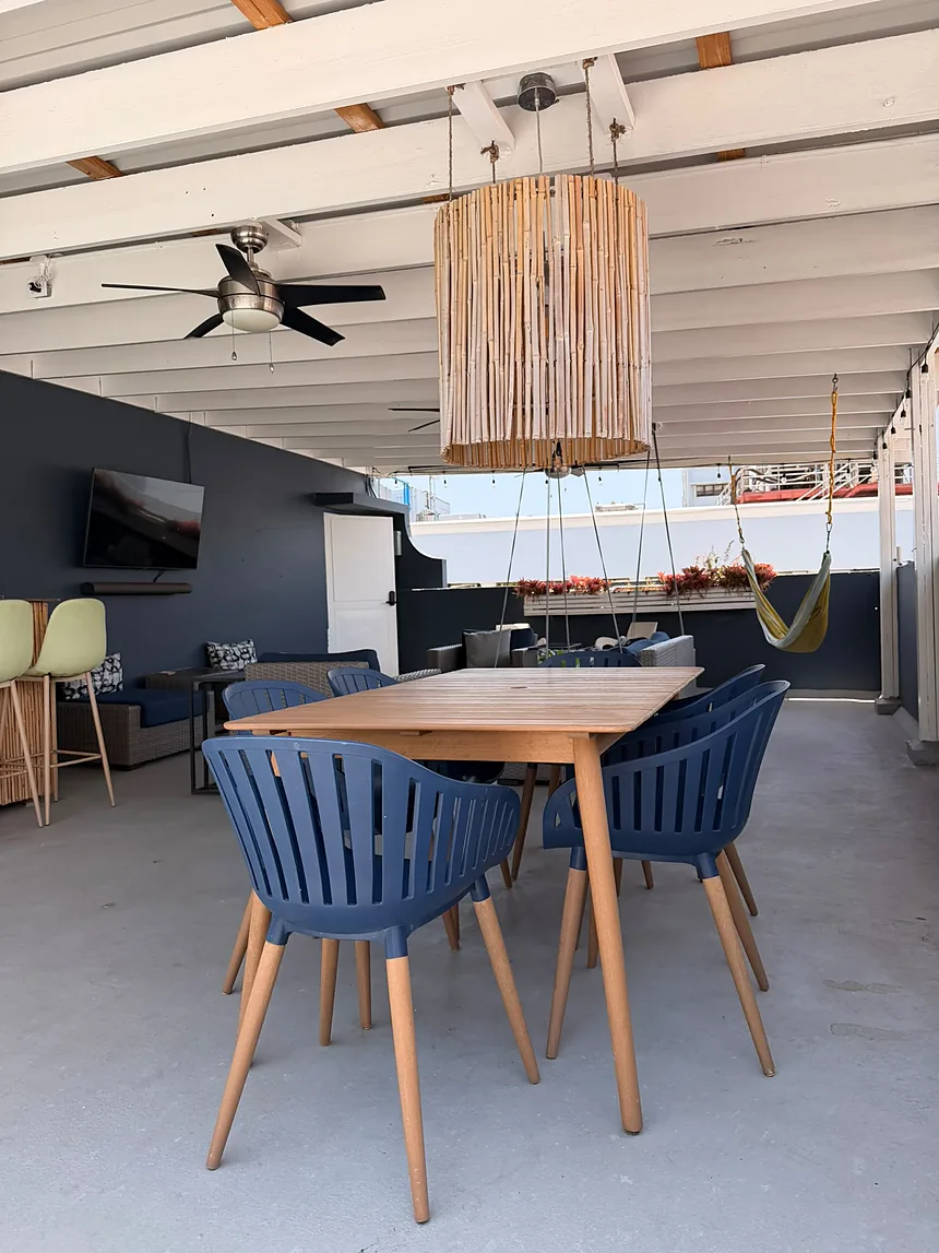 Terraza techada de un Airbnb con mesa de comedor de madera y sillas azules
