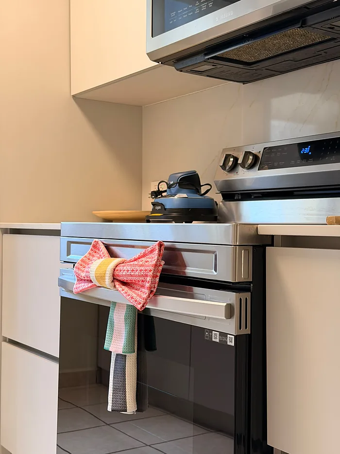 Paño de cocina doblado en forma de lazo sobre la puerta del horno de un Airbnb