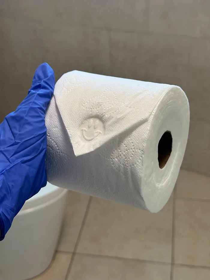 Mano con guante doblando en punta el papel higiénico del baño de un Airbnb