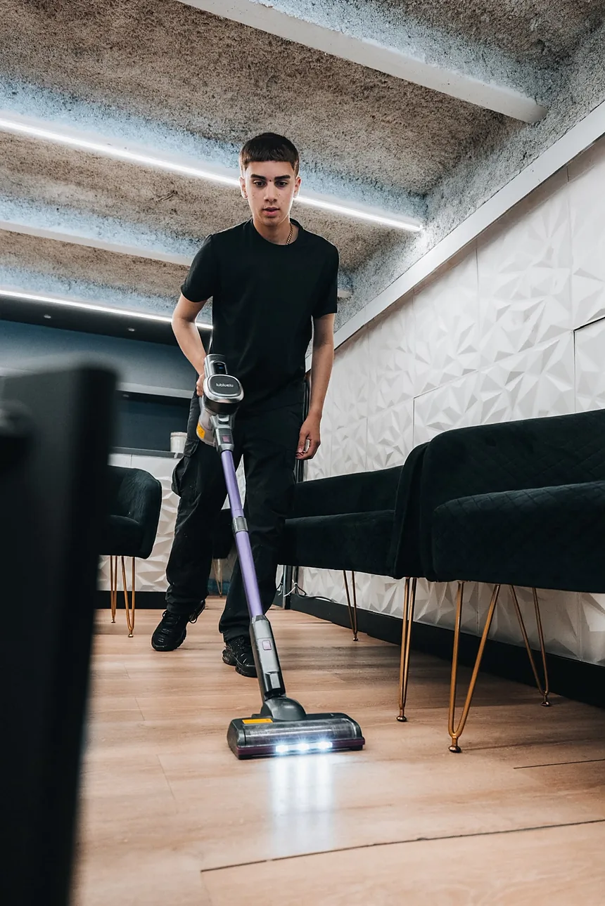 Empleado de Clean Vibes aspirando el lounge de un local con sillones de terciopelo