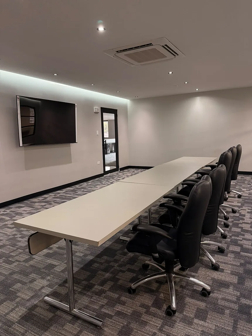 Sala de conferencias con mesa larga y sillas ejecutivas, limpia y lista para reunión